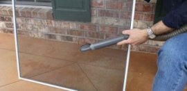 Cleaning window screens with a vacuum cleaner and upholstery brush attachment.